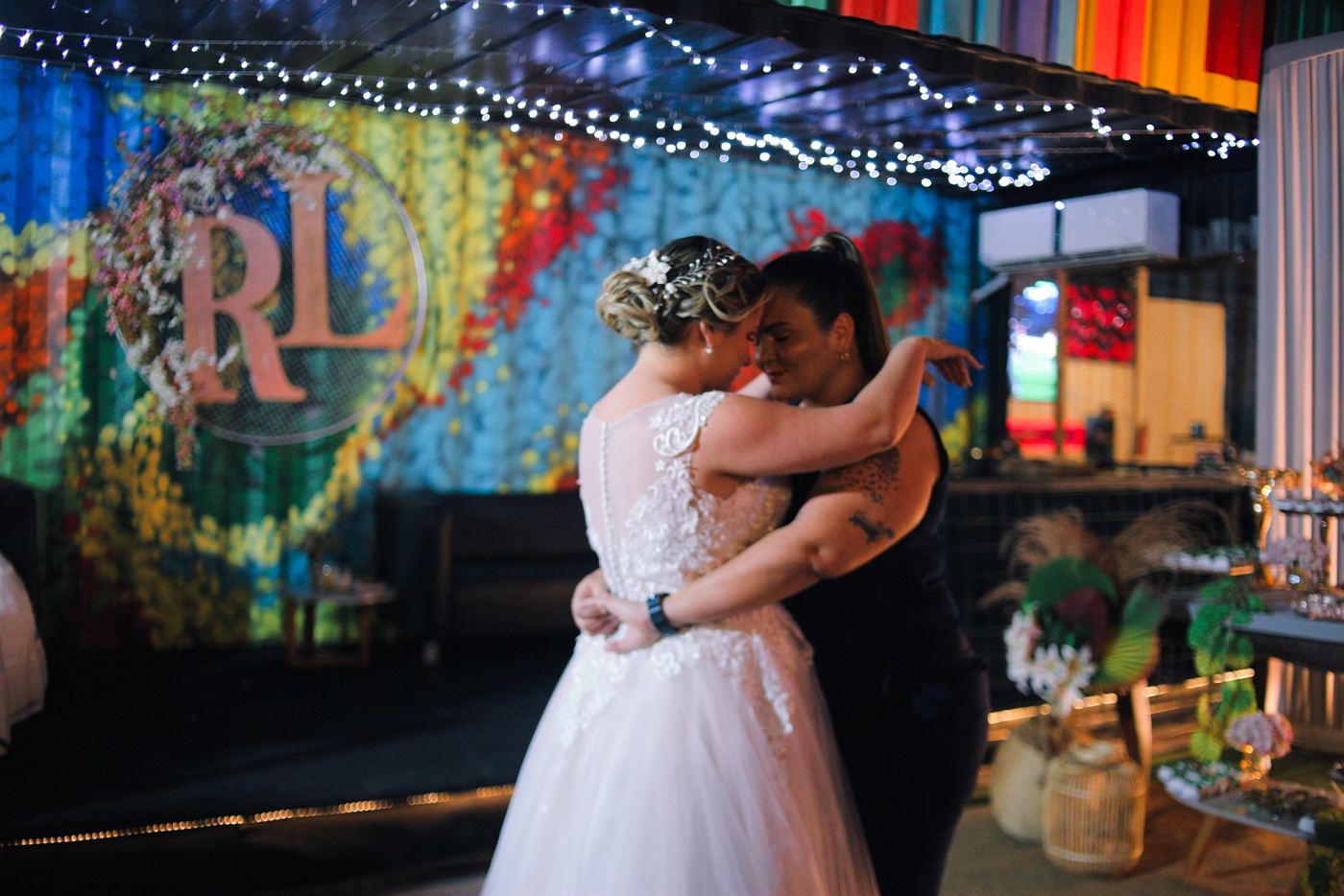 Rox e Lay dançando no casamento, em frente ao painel RL